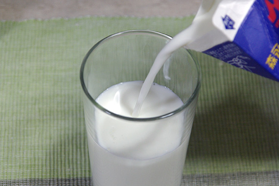 牛乳パック内の牛乳をコップ一杯分減らしている
